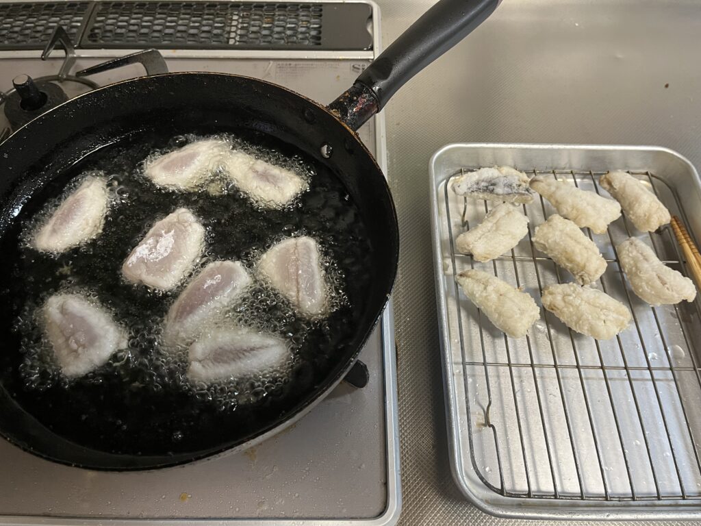 片栗粉をまぶしたトビウオを揚げる