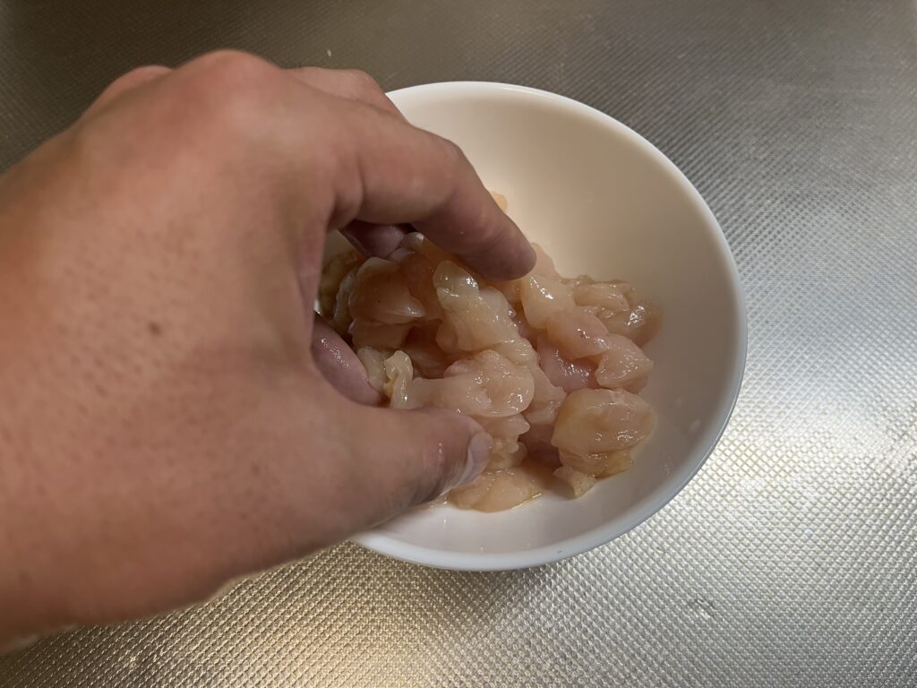 切ったササミに酒、醤油、味の素を加えて揉み込んでいる様子