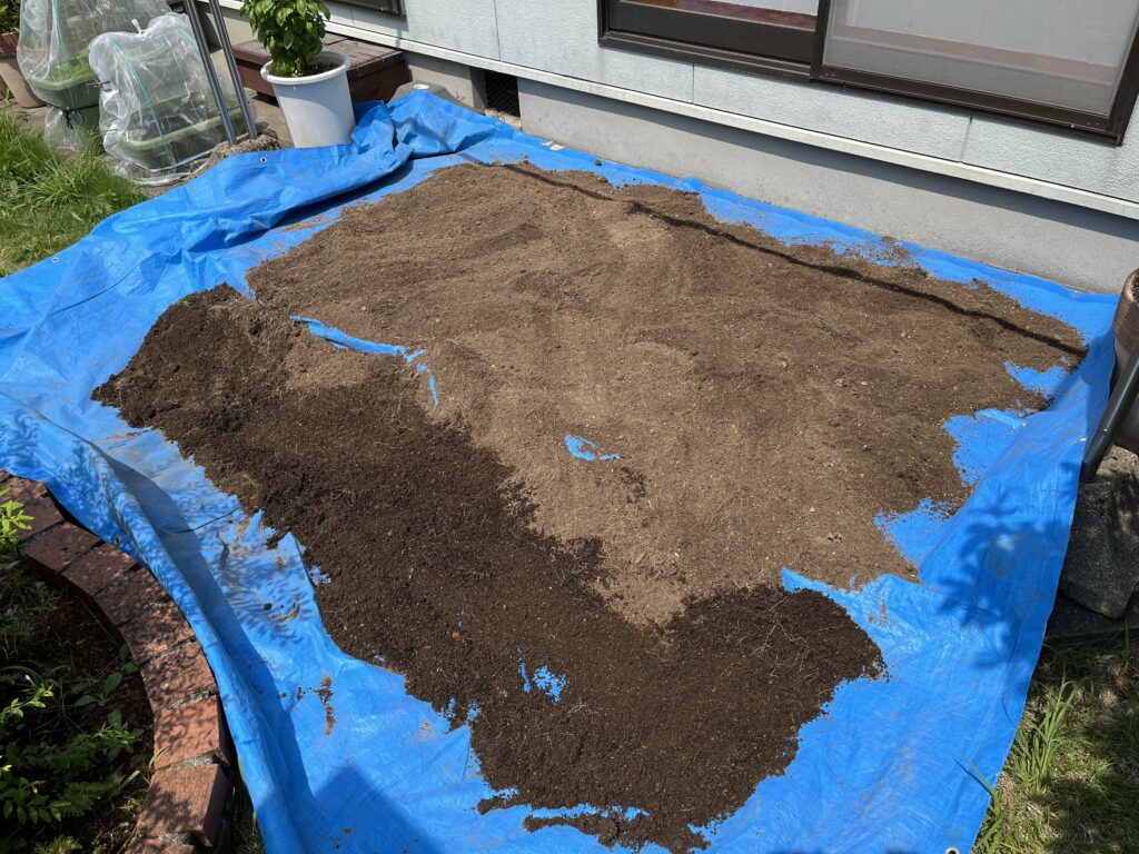 天日干しのためにブルーシートの上に広げたプランターの土