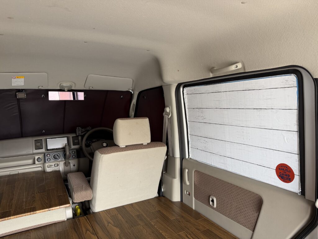 エブリイの車内に、フロントは趣味職人サンシェード、サイドは100均DIYサンシェードを取り付けた車中泊仕様の様子