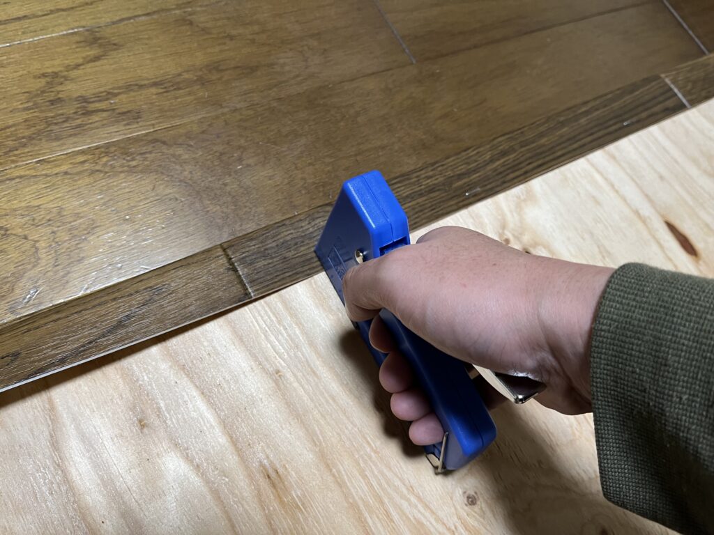 ダイソーのタッカーでクッションフロアを留めている様子