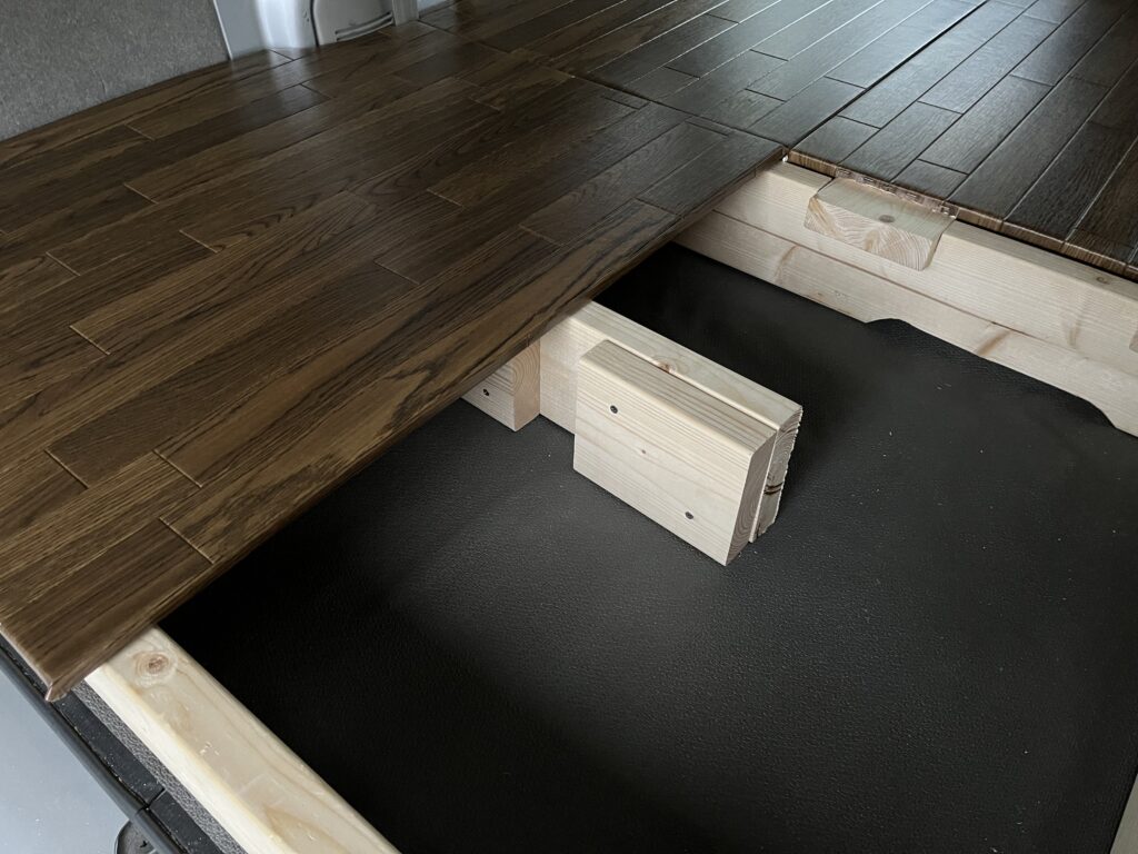 端材を組み合わせて作った支持足を床下に設置している様子