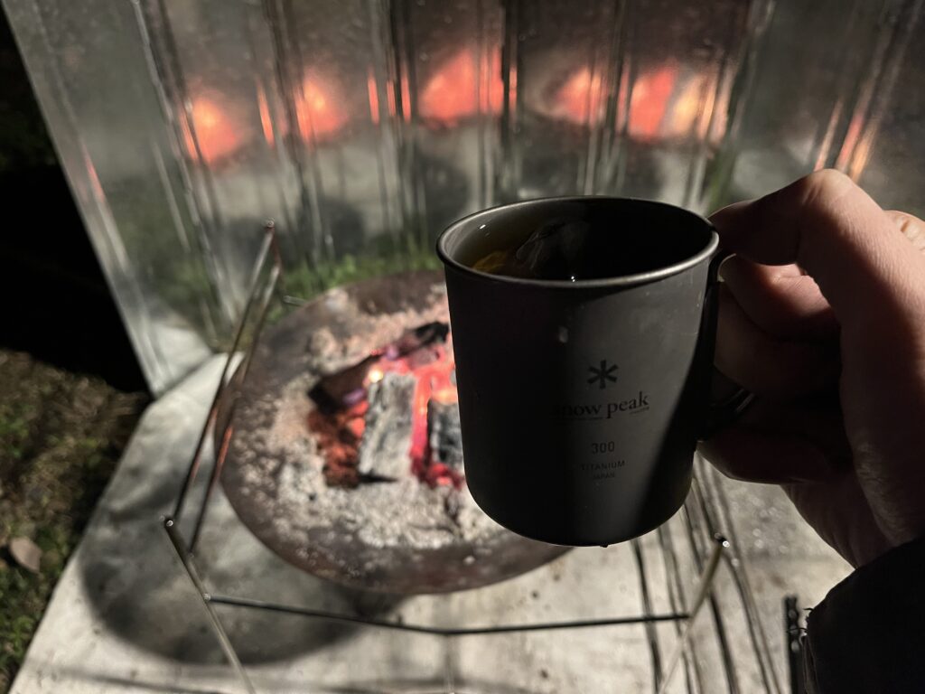 焚き火を背景にしたハイボールのマグカップ