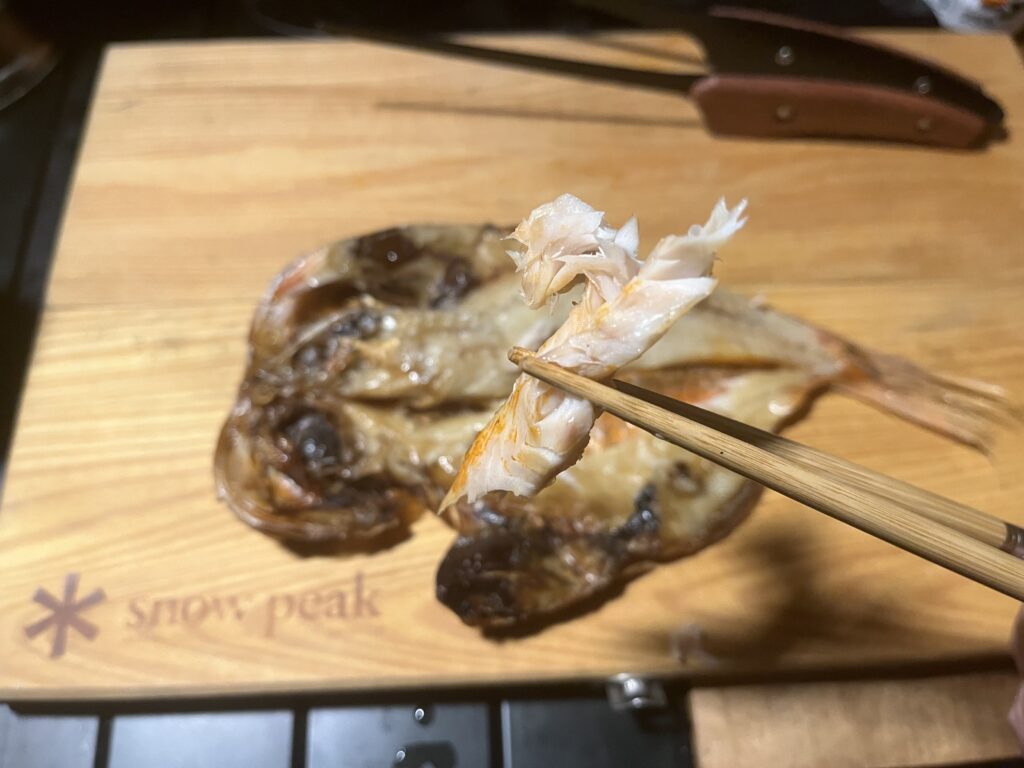 焼き上がった干物のほぐした身を箸でつまんでいる様子