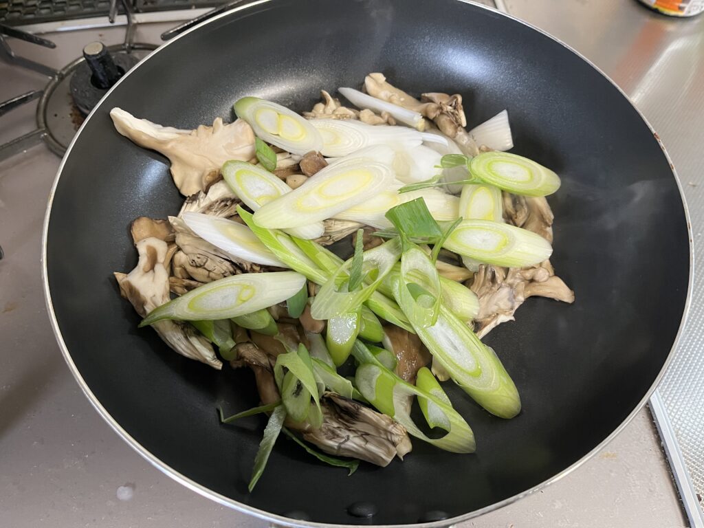 焼き目がついた舞茸のところにカットした長ネギを入れた様子