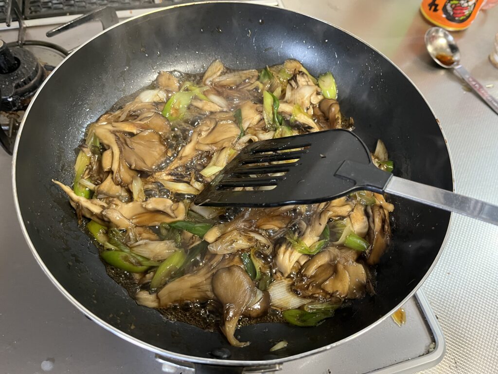 ネギがしんなりしたところに調味料を入れ、絡めている様子