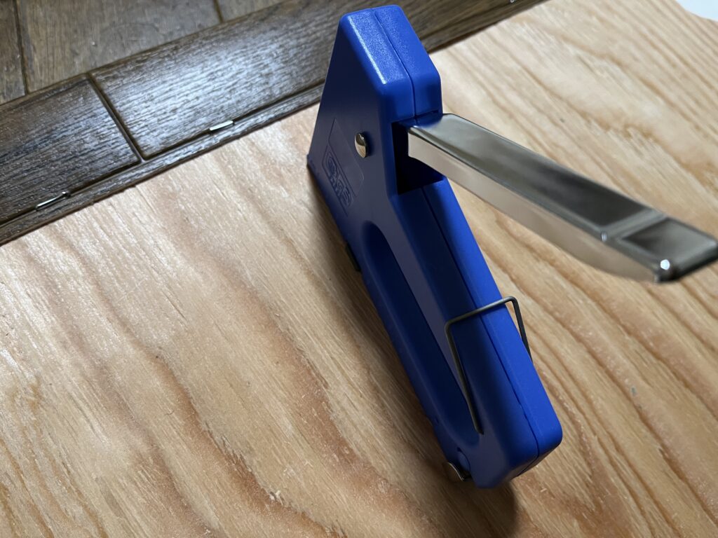 ダイソータッカーでクッションフロアを板に留めている様子