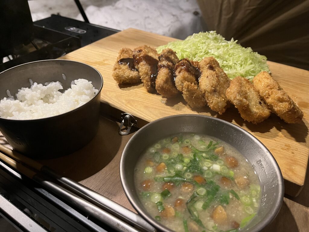 焚き火横のテーブルに並んだヒレカツ定食