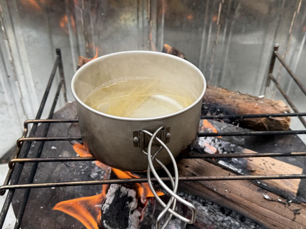 焚き火でパスタを茹でている様子