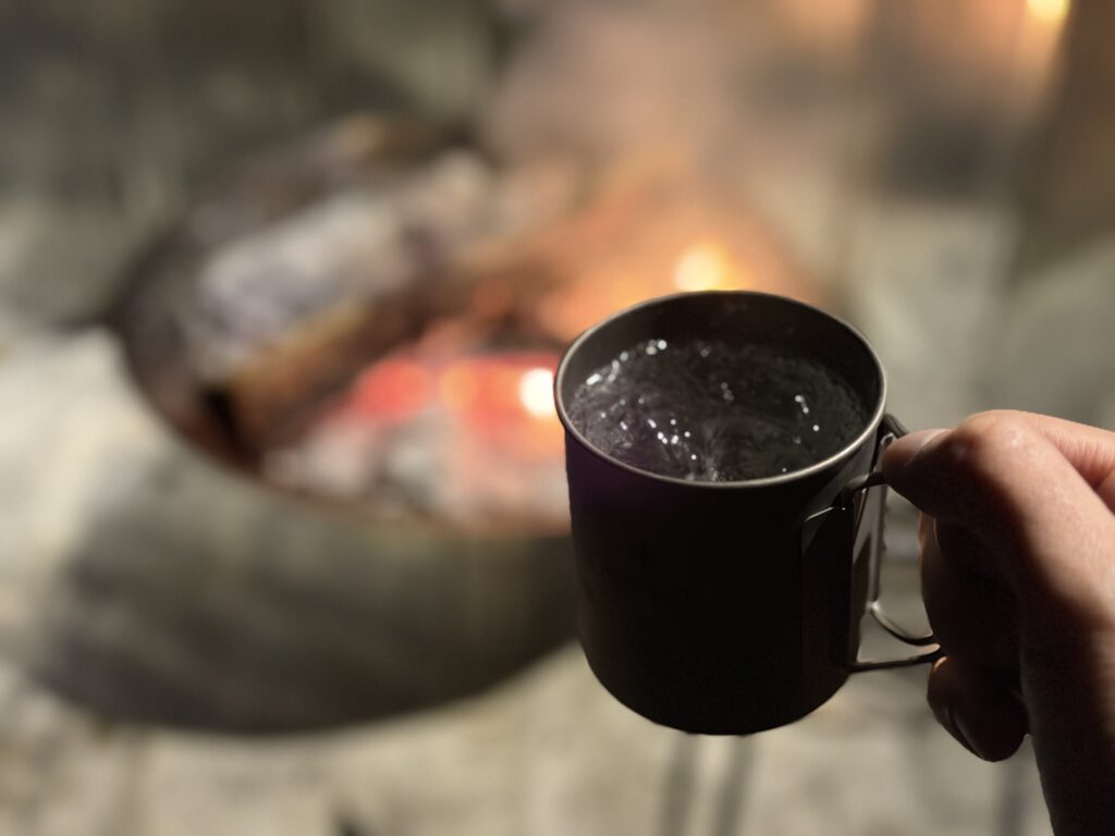 焚き火を眺めながら芋焼酎ソーダ割を飲んでいる様子