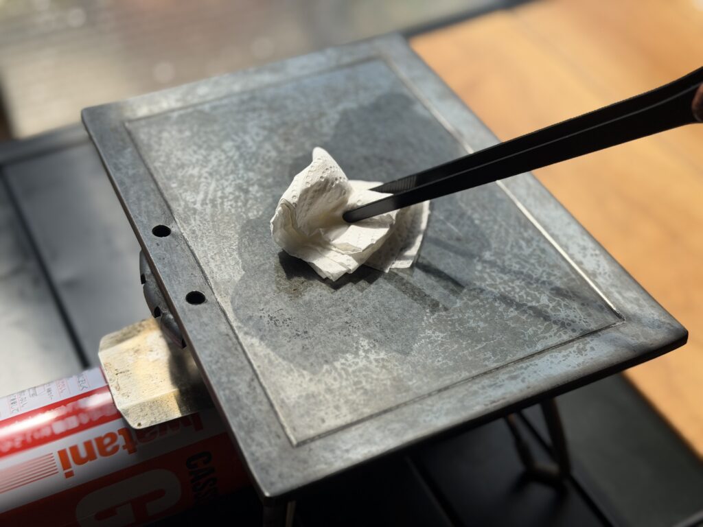 鉄板を洗い、加熱して水分を飛ばしたあとに、油を薄く塗っている様子