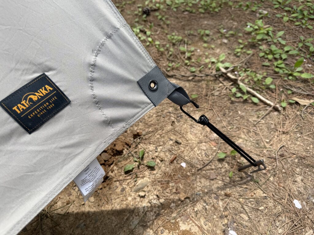 カーサイドタープの固定にストレッチコードを使用してペグに接続している様子