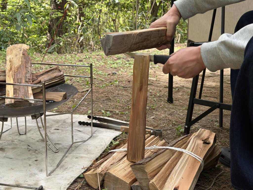 キャンプサイトでナイフと薪を使ってバトニングをして薪を割っている様子