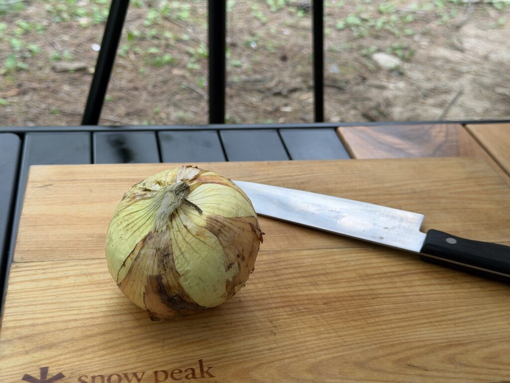 まな板の上に新玉ねぎと包丁が置かれて、調理の準備をしている様子
