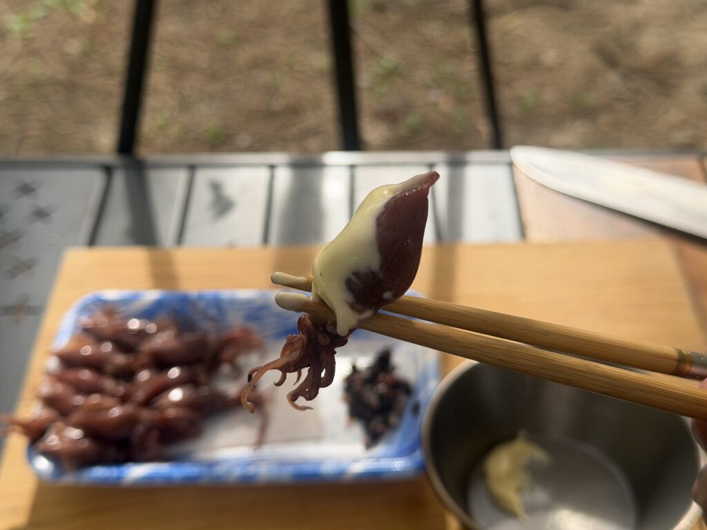 箸でつまんだホタルイカにマヨネーズをつけて食べている様子と、トレーに並んだホタルイカ