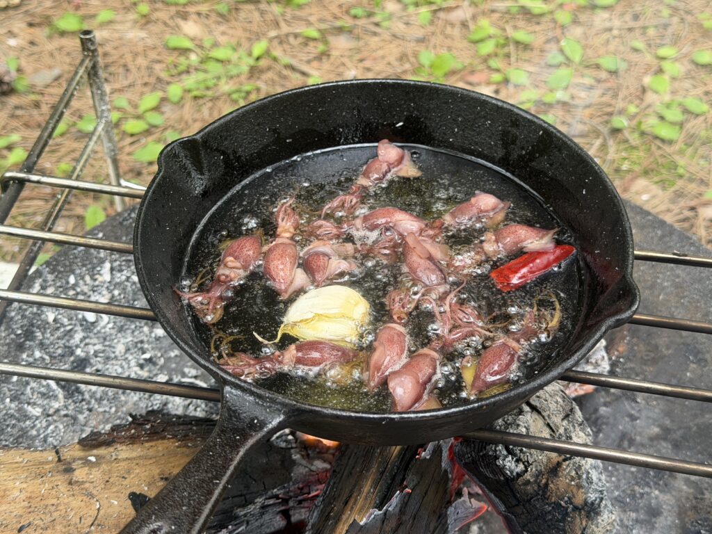 スキレットでホタルイカとニンニク、唐辛子をオリーブオイルで加熱しているアヒージョの様子