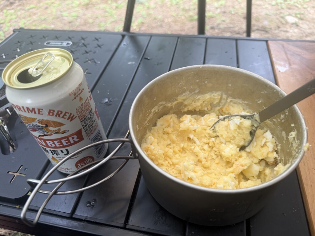 クッカーの中で混ぜられたポテトサラダと横に置かれたビールの様子