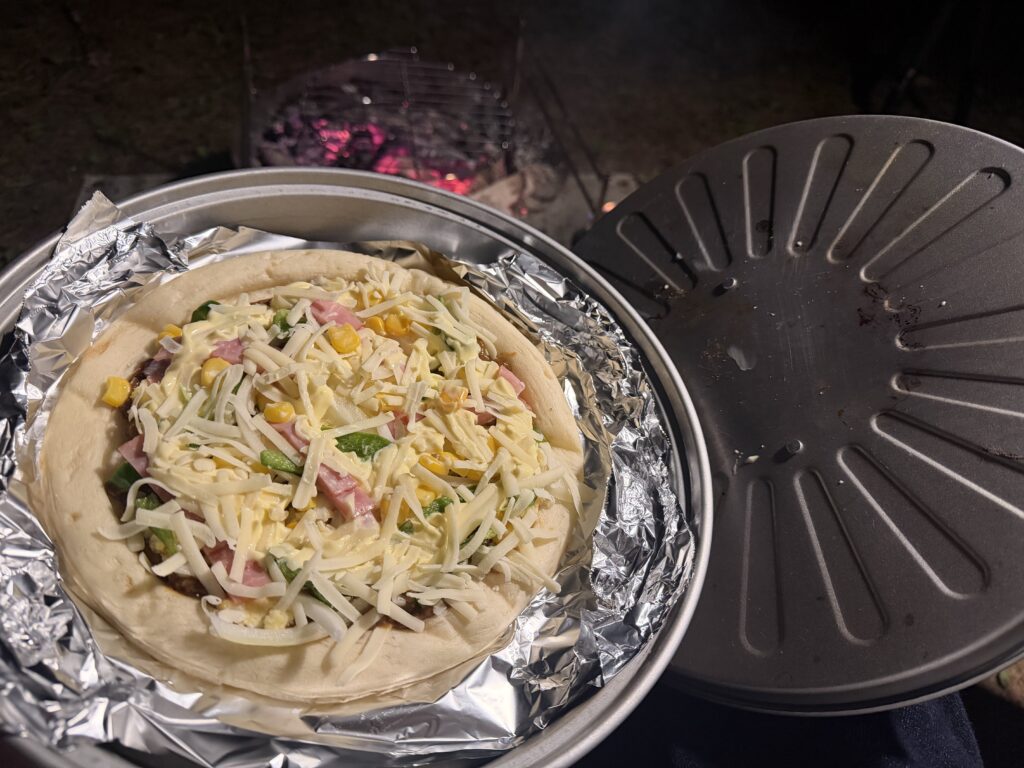 アルミホイルを敷いたピザグリルに具材を乗せたピザを入れ、フタをして火にかける前の様子