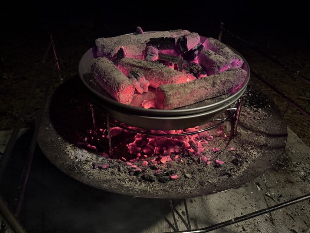 キャプテンスタッグのピザグリルのフタ上に成形炭を多めに置き、下火と上火でピザを焼いている様子