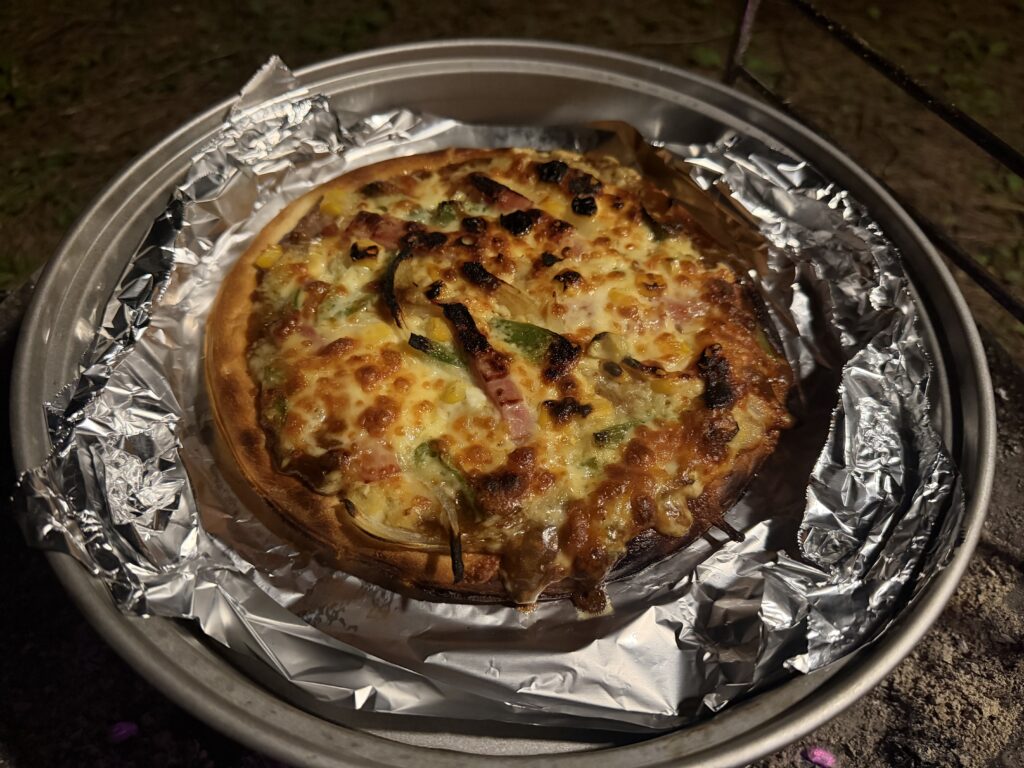 キャプテンスタッグのピザグリルで焼き上げたカレーモントレー風ピザの焼き色と焦げ具合を確認している様子。