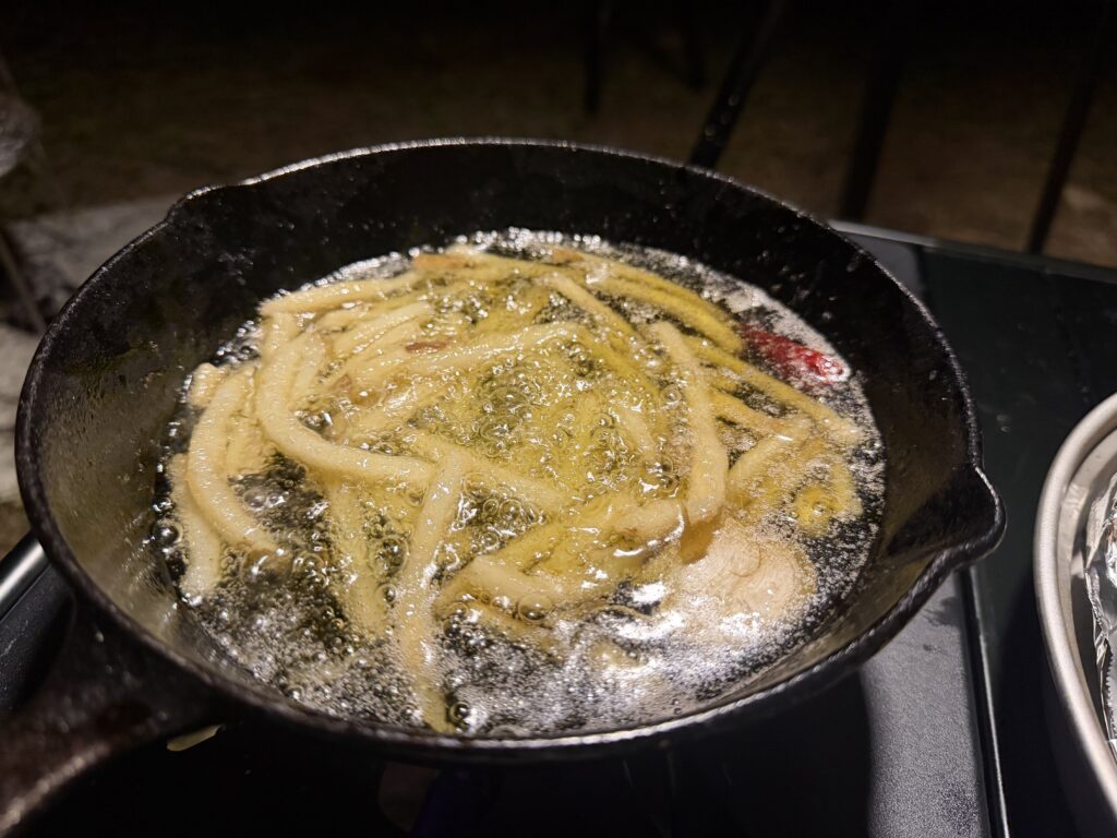 ホタルイカのアヒージョで残った油を使い、スキレットでフライドポテトを揚げている様子