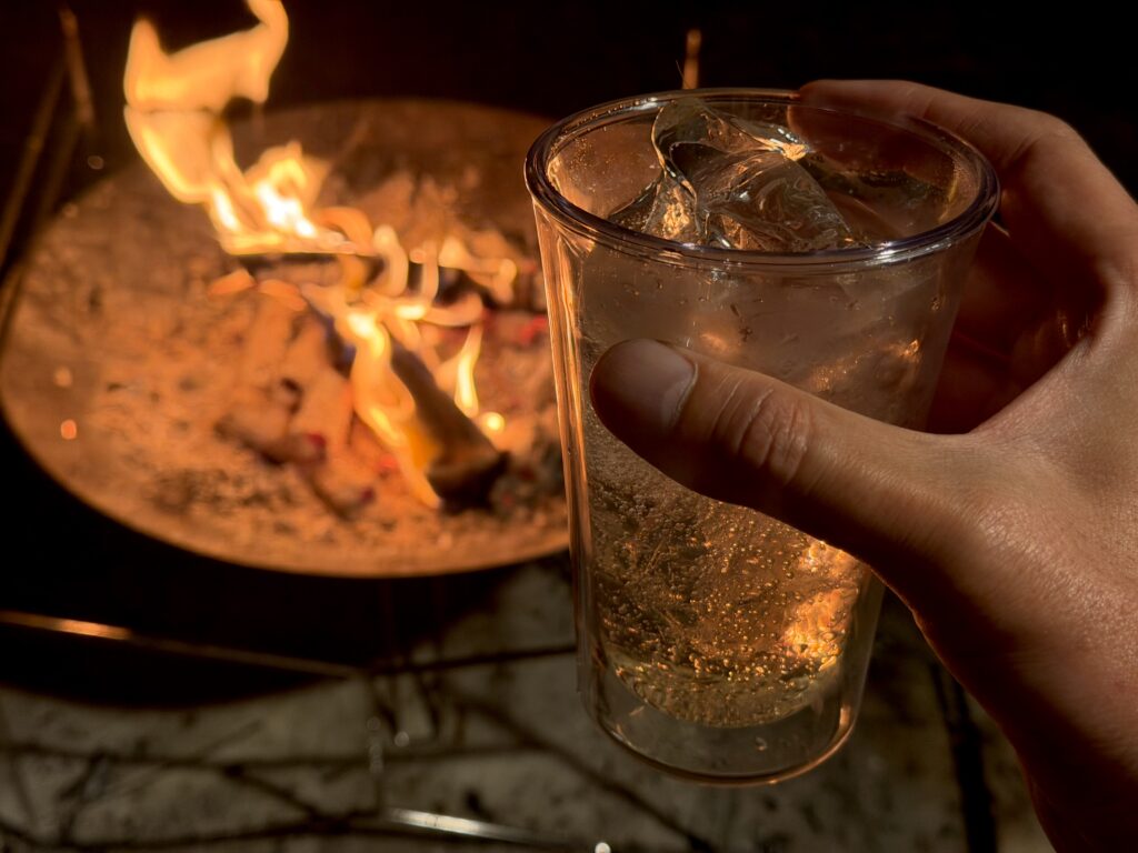 夕食後に終わりかけの焚き火を眺めながら、手に持ったハイボールを飲んでいる様子