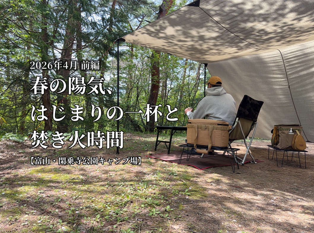 林間のキャンプサイトでカーサイドタープの下に座り、椅子に腰かけてビールを飲みながらくつろいでいる様子