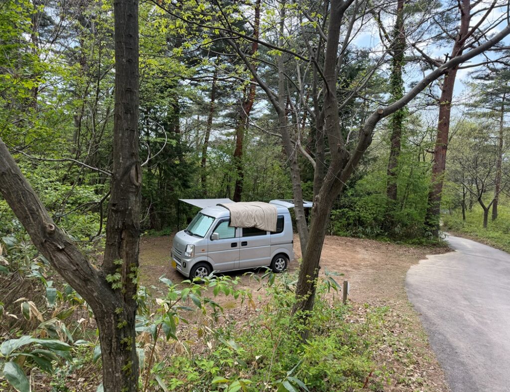 晴れた昼のキャンプ場で、エブリイの上にシュラフを広げて天日干ししている様子