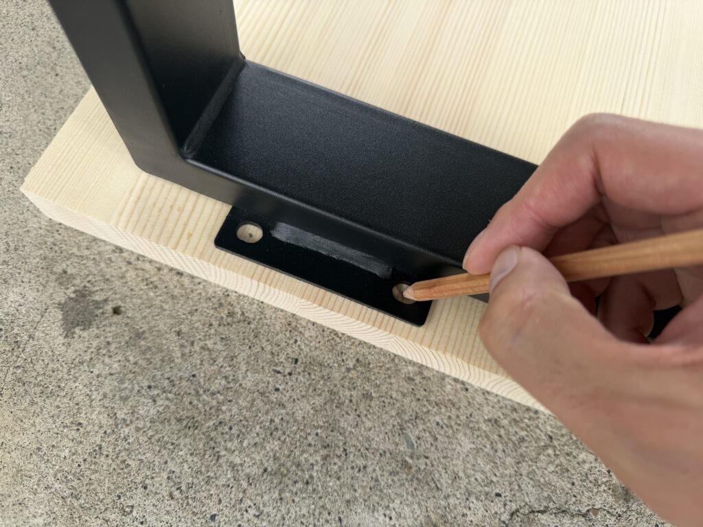 テーブル脚の取り付け位置を確認しながら、赤松集成材に鉛筆で印を付けている様子