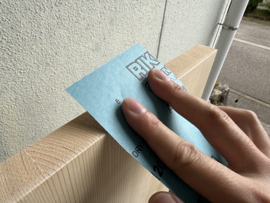 サンドペーパーを使ってテーブル天板の角を手作業で面取りしている様子