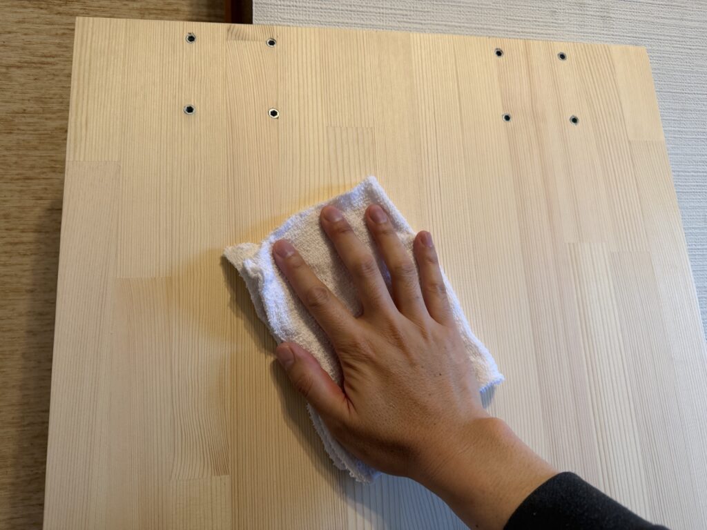 研磨後の赤松集成材を固く絞った布で拭き、木粉を取り除いている様子