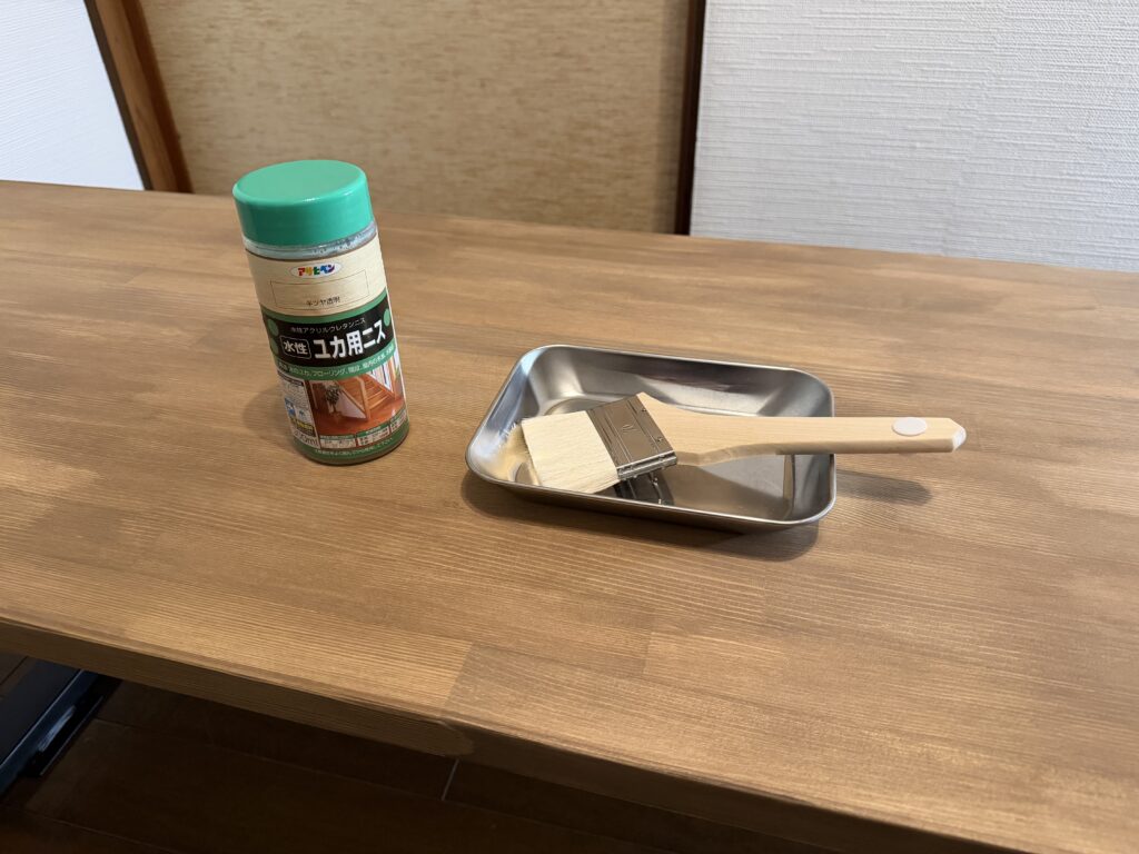 天板の上にユカ用ニスと刷毛と容器を並べて準備している様子