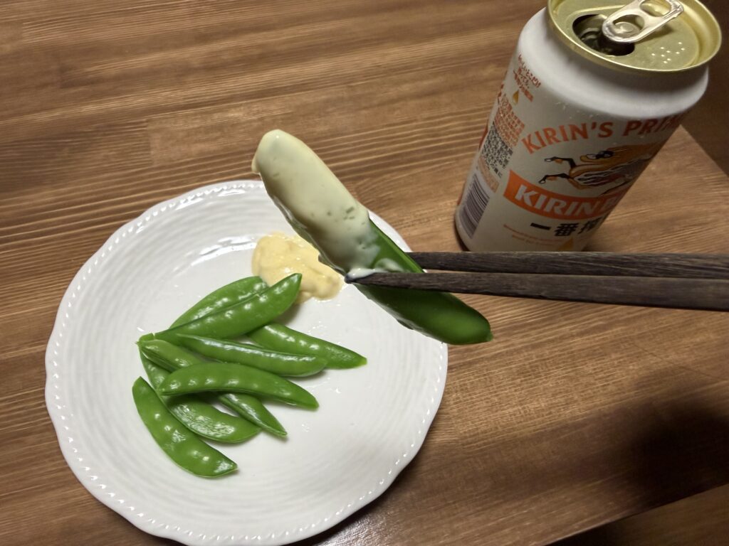 マヨネーズをつけたスナップエンドウを箸で持ち上げている様子