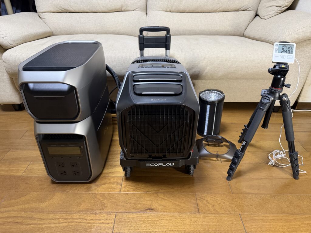 リビングのソファ前にEcoFlow WAVE 3、ポータブル電源、排熱ダクト、室内外温度計を並べて試運転準備をしている様子