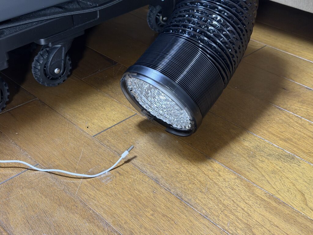 EcoFlow WAVE 3の排熱ダクト出口の前に、室内外温度計のコード先センサーを置いて排熱温度を測ろうとしている様子。