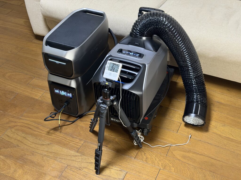 リビングでEcoFlow WAVE 3をポータブル電源に接続し、排熱ダクトと室内外温度計をセットして試運転している様子。