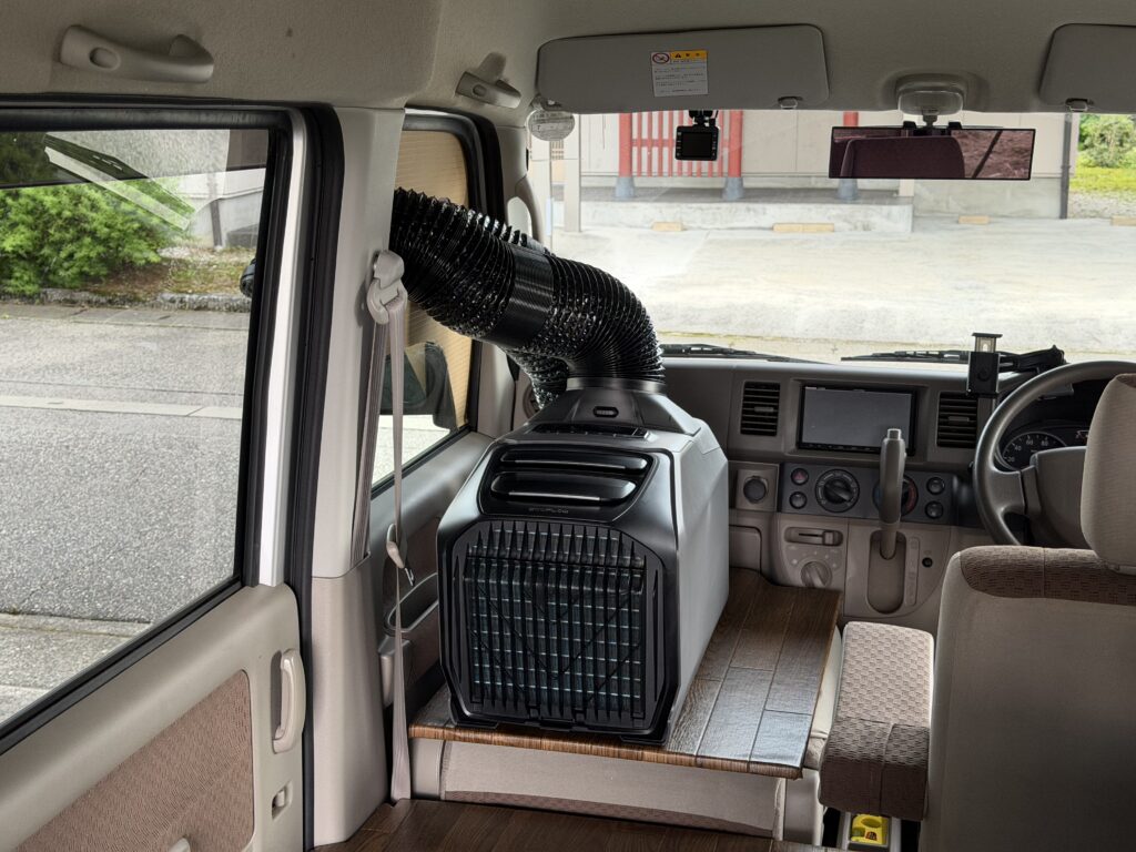エブリイDA64Vの助手席にEcoFlow WAVE 3を仮置きし、助手席窓のダンボール型紙へダクトを接続して取り回しを確認している様子。