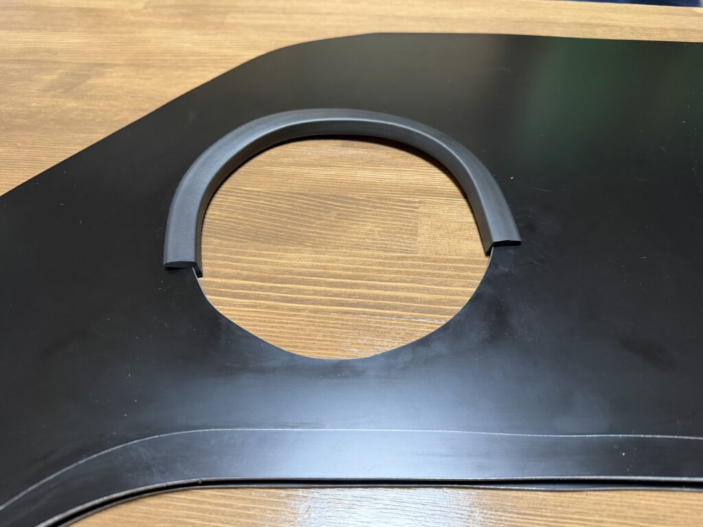 黒いアルミ複合板のダクト穴上部に、はさみ込み式の黒いクッション材を取り付けた様子