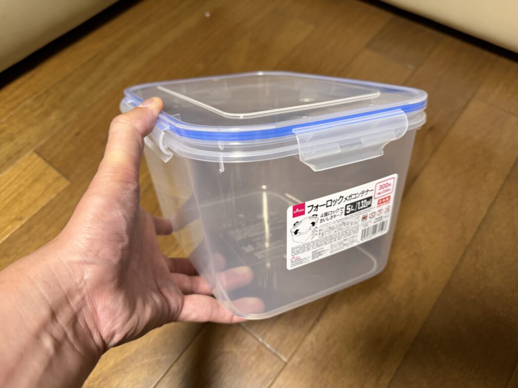 手で持った5Lのフタ付き透明保存容器
