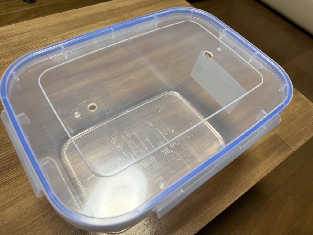 5Lの透明容器のフタに、排水ホース用の穴と空気抜き用の穴を開けた様子