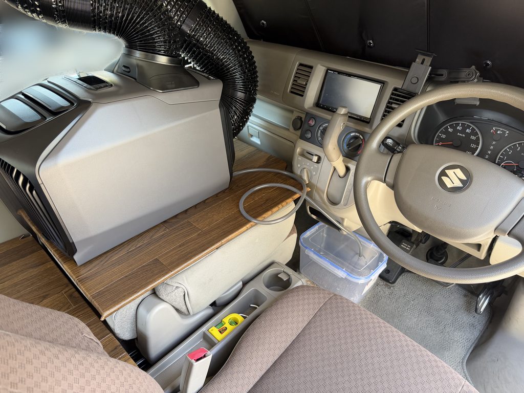 エブリイの助手席側に設置したEcoFlow WAVE 3から、排水ホースを5Lの透明容器へつないだ車内の様子