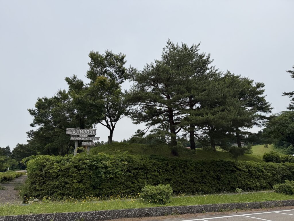 曇り空の閑乗寺公園キャンプ場入口と花を終えたツツジ