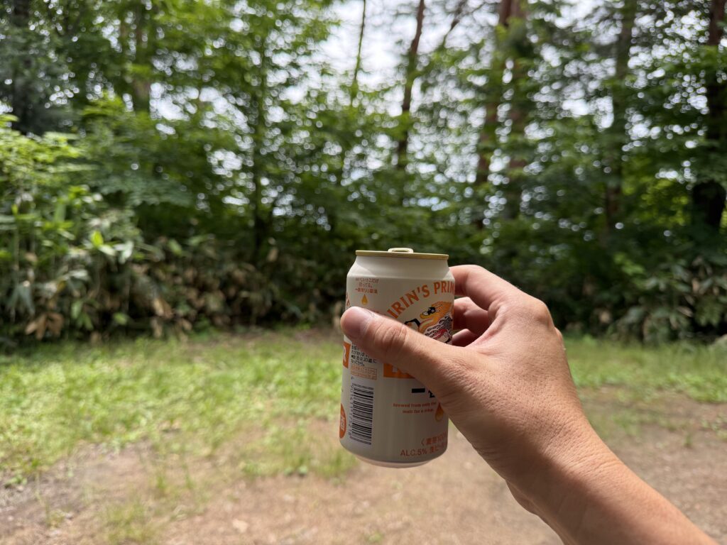 静か森19番サイトの緑を眺めながら缶ビールで乾杯する様子