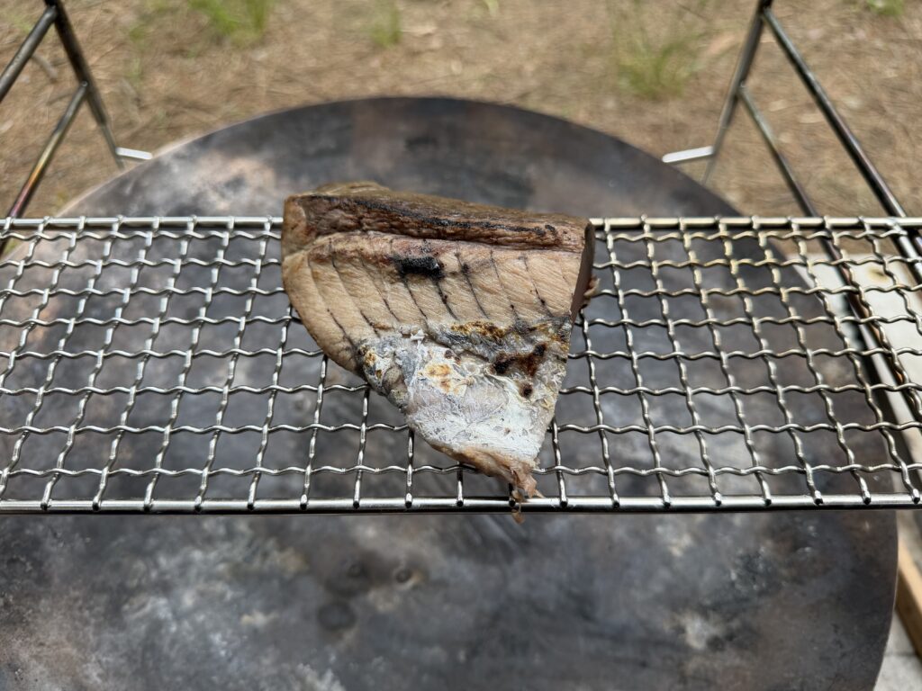 焚き火台の焼き網の上にカツオのたたきを乗せた様子