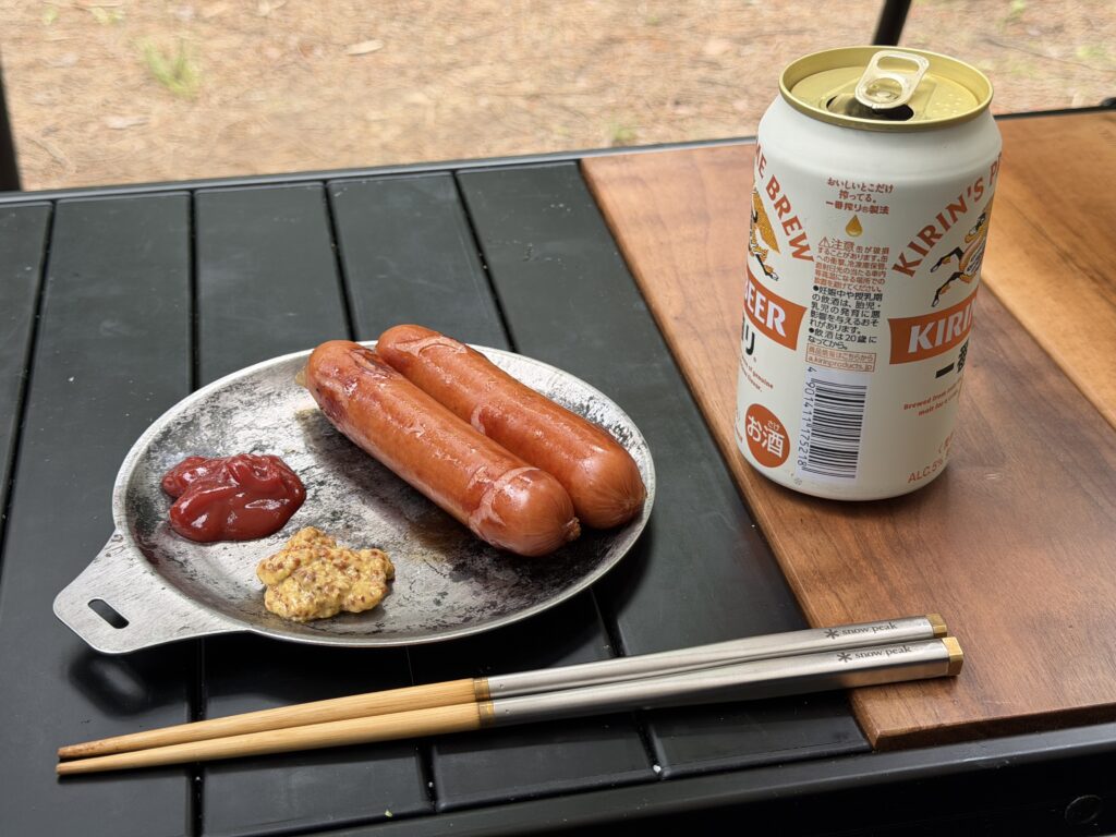 焚き火で焼いて皮が裂けたジョンソンヴィルに、ケチャップと粒マスタードを添えた様子