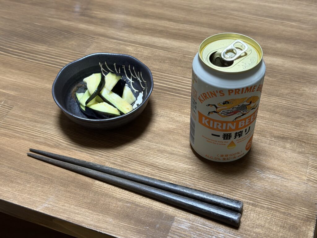 初収穫したナスで作った浅漬けを、缶ビールと一緒に食卓へ並べた様子