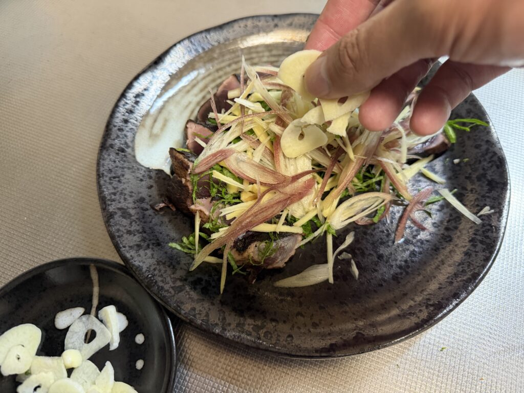 カツオのたたきにミョウガ、しょうが、大葉、にんにくなどの薬味をのせている様子