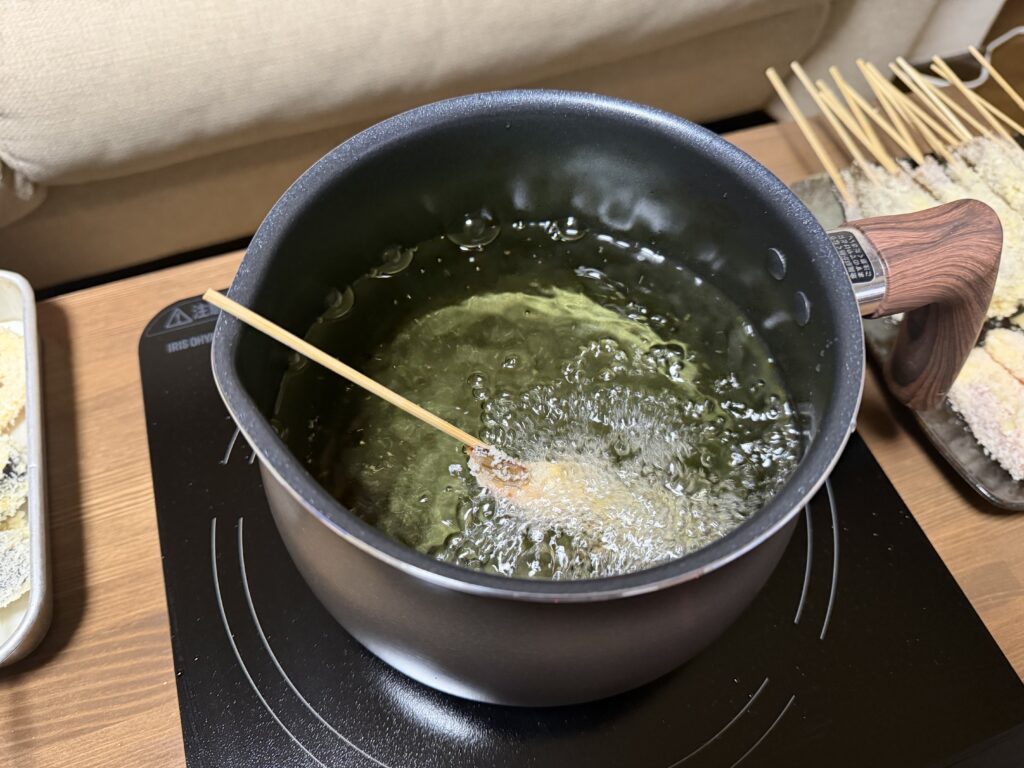 マルチポットの油の中で串揚げを1本揚げている様子