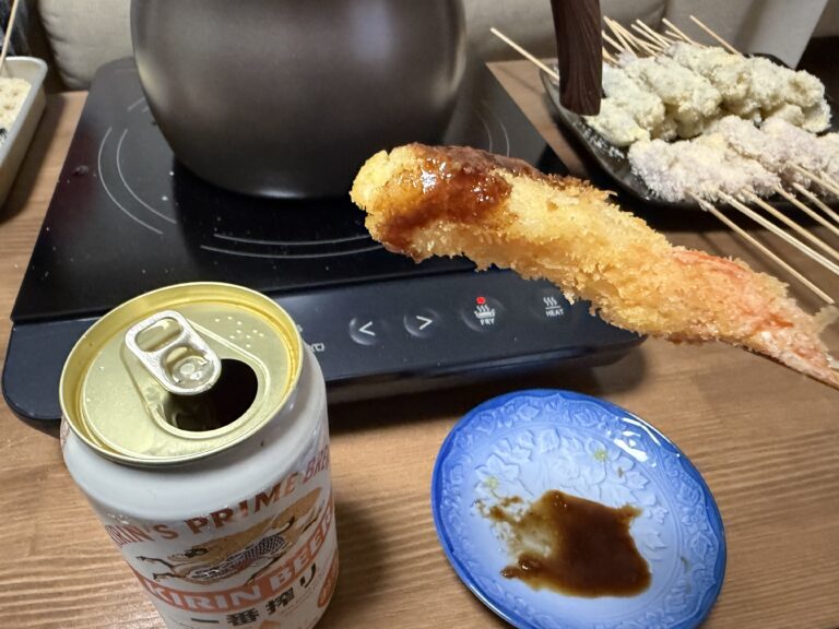 IHコンロで揚げたエビの串揚げを持ち上げている様子