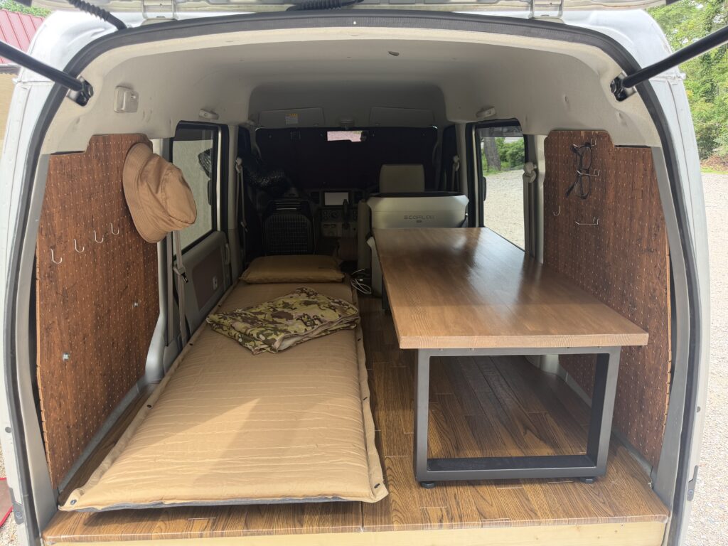 エブリイの車内で、寝床用マットの横に自作テーブルを置いた車中泊レイアウト